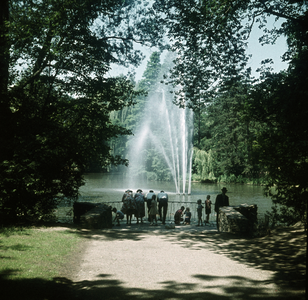 119346 Afbeelding van enkele toeschouwers bij de fontein in de vijver van het Julianapark te Utrecht.